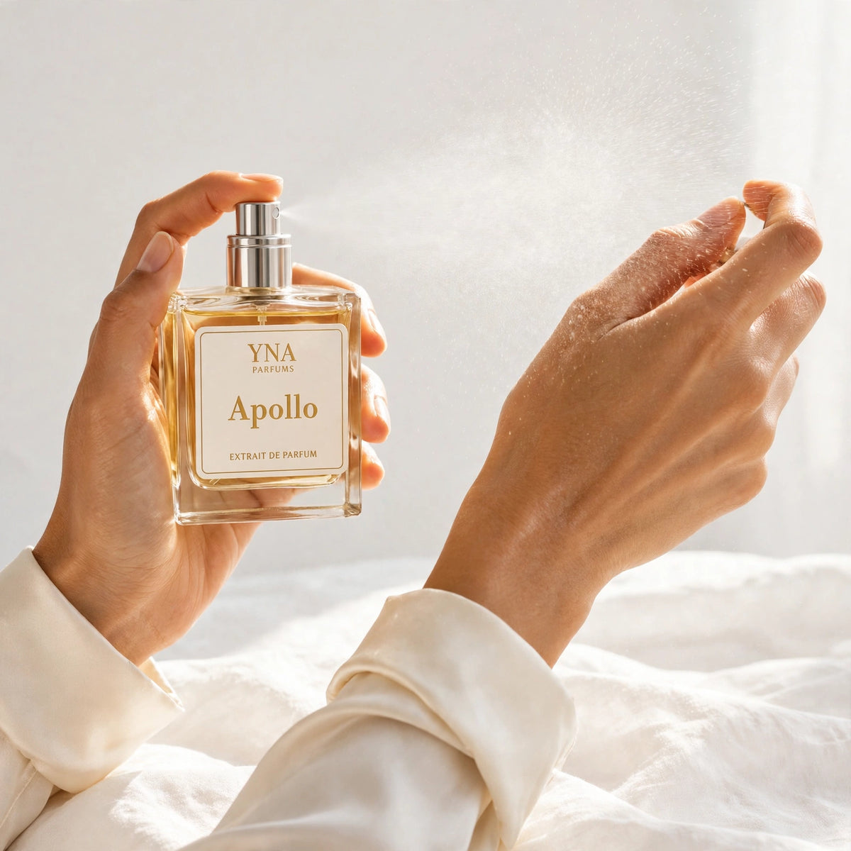 Hand spraying YNA Parfums Apollo Extrait de Parfum 50ml onto a wrist, mist in the daylight